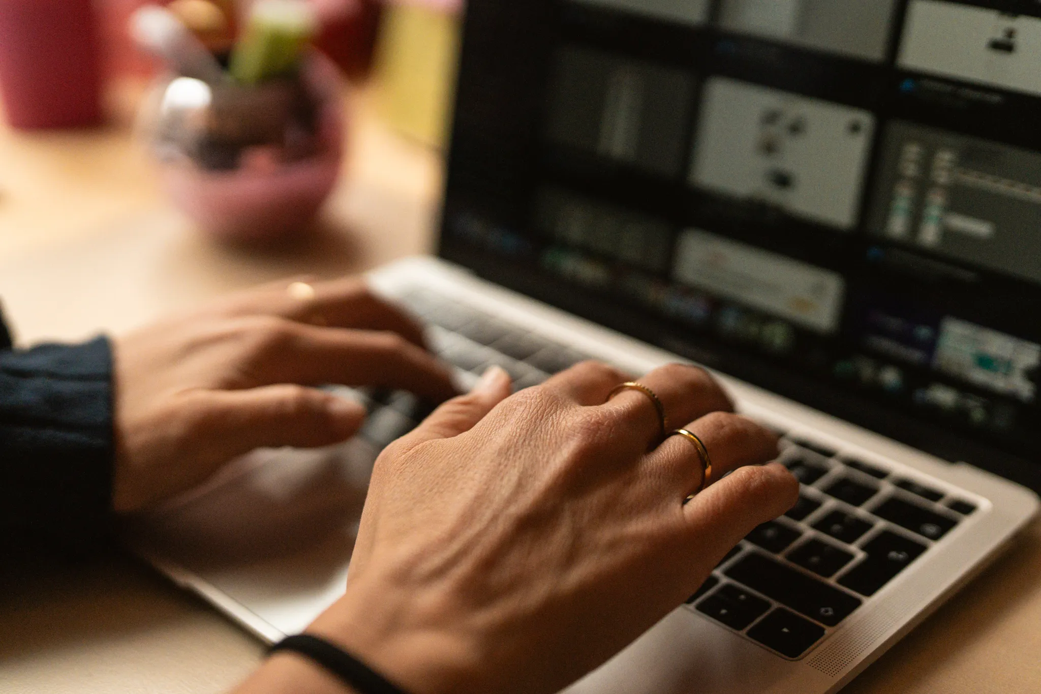 Person arbeitet an einem Laptop und gibt Text ein, während der Bildschirm unscharf im Hintergrund ist