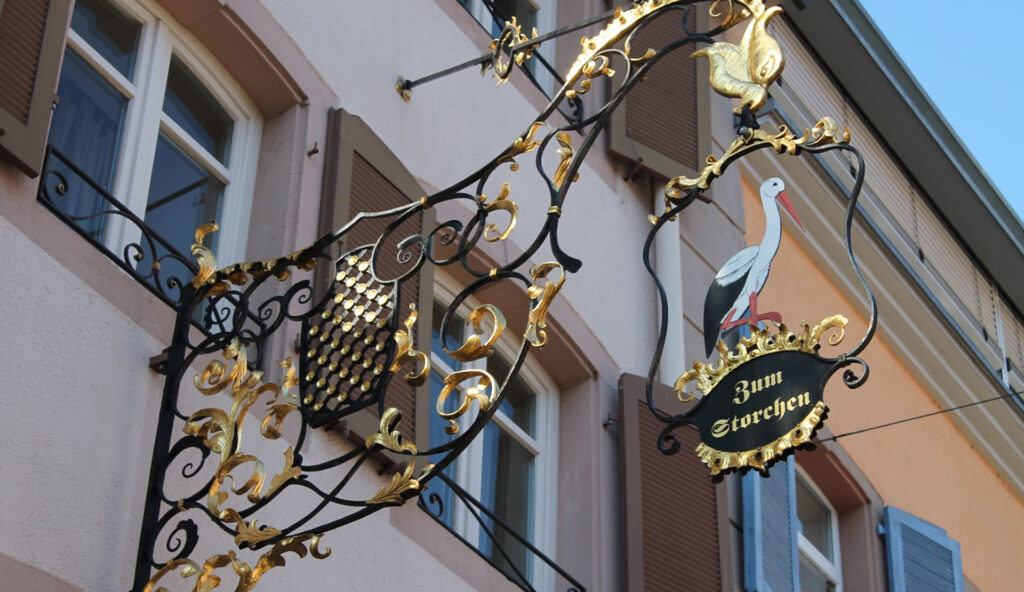 Zum Storchen: Detailaufnahme eines dekorativen Hotelschilds an einer historischen Hausfassade