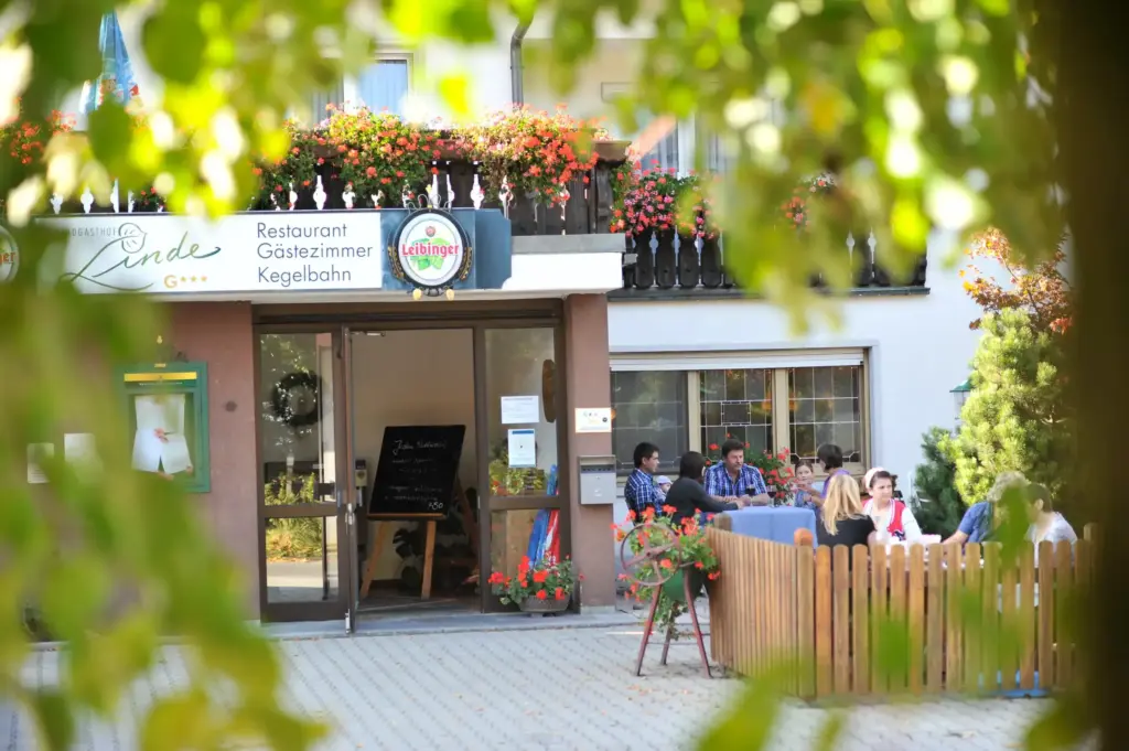 Landgasthof Linde: Außenbereich eines Cafés oder Hotels mit Terrasse, Gästen und blühenden Pflanzen