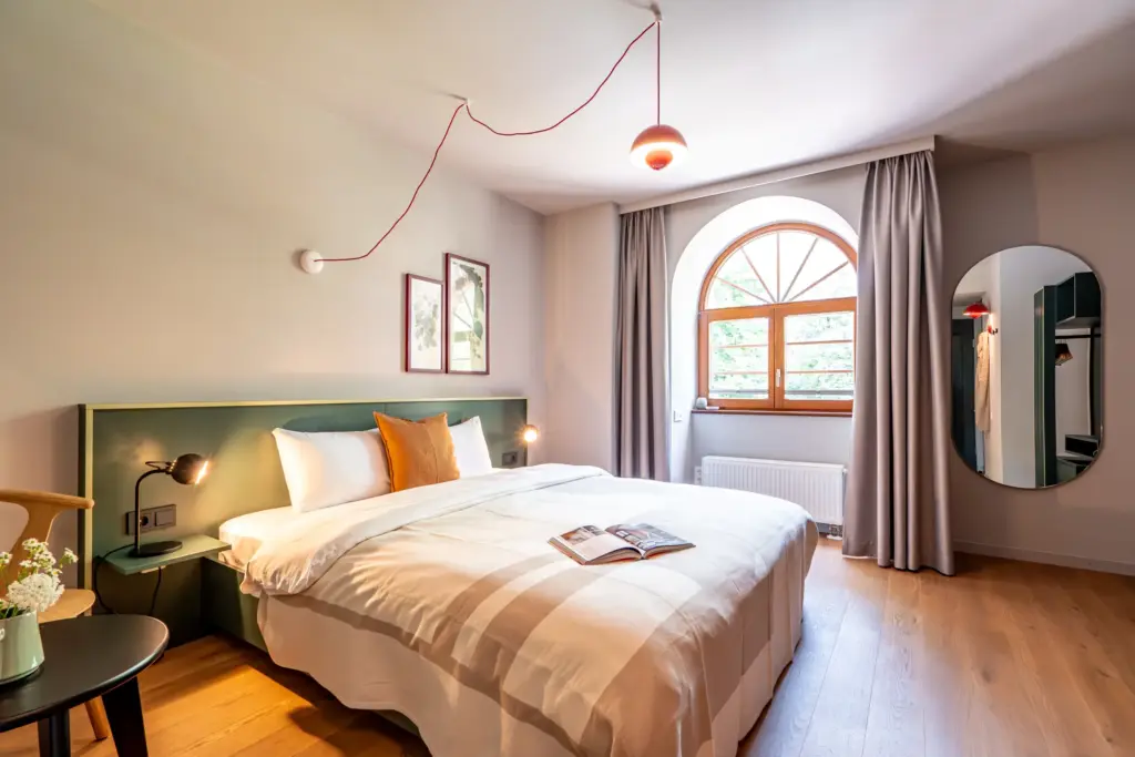 Hotel Deville: Helles Hotelzimmer mit Doppelbett, Holzbalkendecke und gemütlicher Atmosphäre