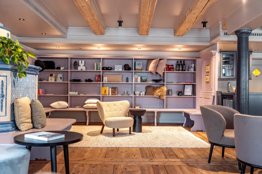 Hotel Deville: Gemütliche Hotellounge mit Bücherregal, Sesseln und warmem Holzfußboden
