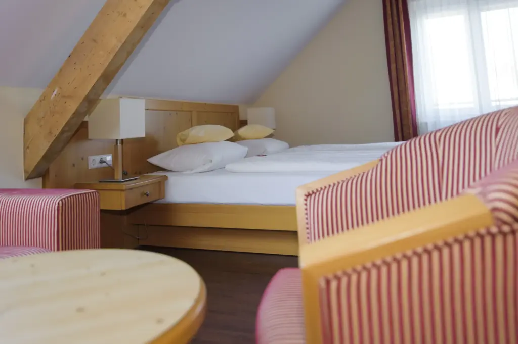 Landgasthof Linde: Komfortables Hotelzimmer mit Doppelbett, Sitzecke und warmen Farbakzenten