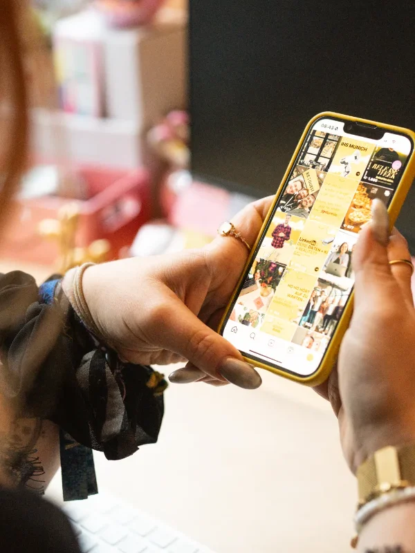 Person mit Handy in der Hand auf dem ein Social Media Feed zu sehen ist